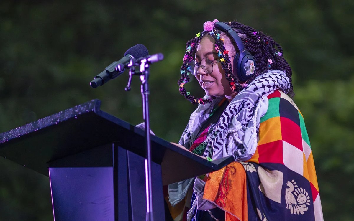 Alora reading at a podium outdoors